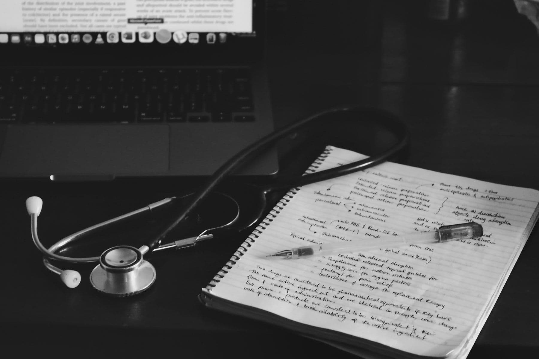 A stethoscope on handwritten notes next to a laptop